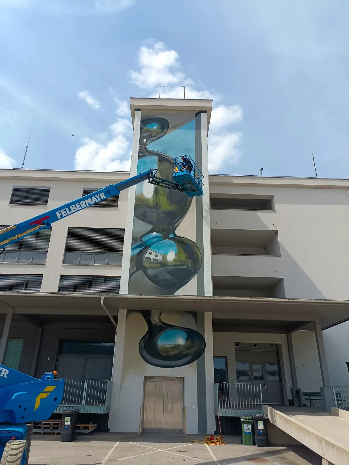 Odeith's anamorphic mural surrounded by the industrial architecture of Mural Harbor in Linz