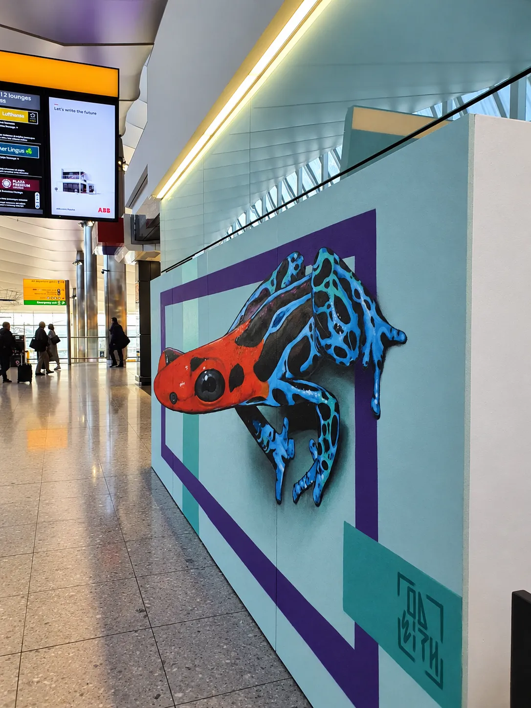 Completed 3D anamorphic blue frog artwork by Odeith in Terminal 4 at Heathrow Airport, showing full optical depth from the main viewer perspective.