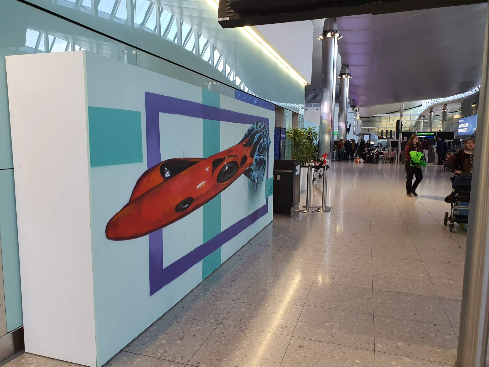 Side-angle view of the Heathrow artwork revealing the stretched distortion of the painted anamorphic illusion across the terminal wall.